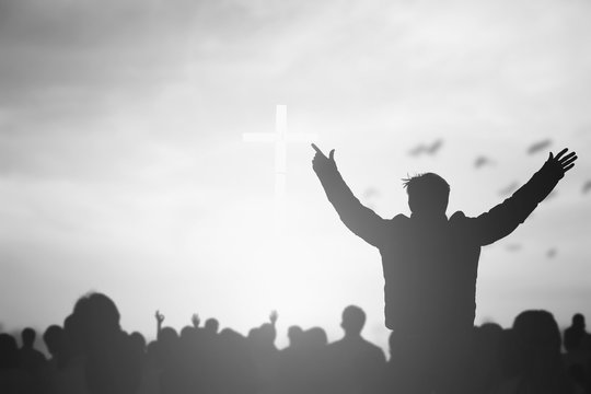 Praise and worship concept: Silhouette human raising hands to praying God on blurred cross with crown of throne sunset background