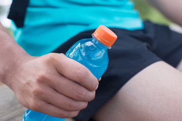 Bottle of energy drink and orange juice in hands of trail runner.