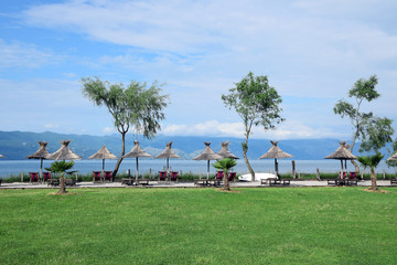 Obraz na płótnie Canvas Straw umbrellas on the Lake Skadar beach. Albania - Montenegro border.
