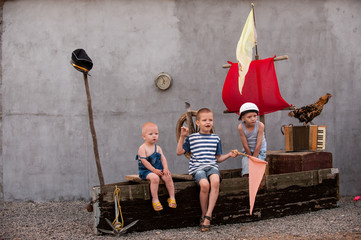 Three cute boys on a pirate ship as sailors on summer evening. Children have fun outdoors. Happy...
