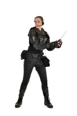 Naklejka premium full length portrait of female soldier wearing black tactical armour, holding a remote control, isolated on white studio background.