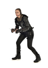 full length portrait of female  soldier wearing black  tactical armour, holding a remote control, isolated on white studio background.