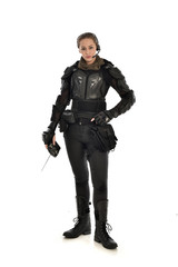 full length portrait of female  soldier wearing black  tactical armour, holding a remote control, isolated on white studio background.
