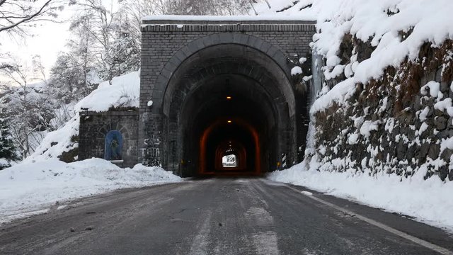 Road with ancient stone tunnel in winter scenic with icicles and snow, Bielmonte, Italy