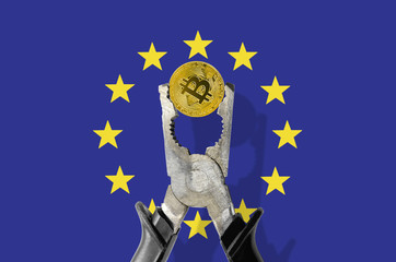 BITCOIN coin being squeezed in vice on the European Union flag background; concept of cryptocurrency bitcoin under pressure. Prohibition of cryptocurrencies, regulations, restrictions or security