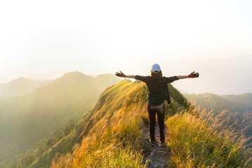 Happy woman traveler raised arms on top of mountain, feel freedom and enjoy nature.