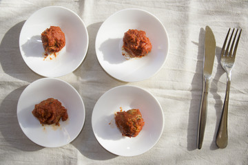 four white saucer with meatballs in tomato sauce