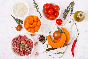 Ingredients for cooking chicken hearts with pumpkin and tomatoes in tomato sauce. The garnish is served with boiled rice. Flat lay. Top view.