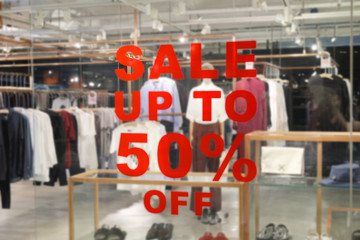 A sign of sale up to 50% off mock up advertise display frame setting over clothes fashion store in shopping mall, Shopping and discount in department store concept.
