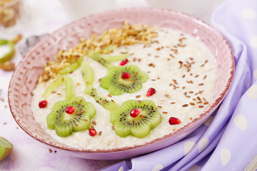 Tasty and healthy oatmeal porridge with kiwi, pomegranate and nuts. Healthy breakfast. Fitness food. Proper nutrition.
