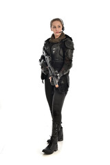 Fototapeta premium full length portrait of female soldier wearing black tactical armour, holding a rifle gun, isolated on white studio background.