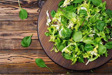 Fresh leaves of mix salad on a wooden background. Flat lay. Top view