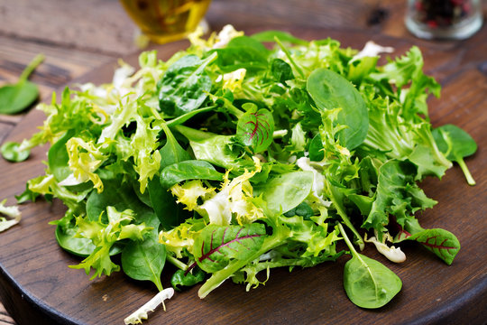 Fresh leaves of mix salad on a wooden background.