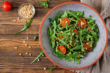 Dietary menu. Vegan cuisine. Healthy salad with arugula, tomatoes and pine nuts. Flat lay. Top view