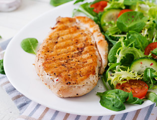 Grilled chicken breast and fresh vegetable salad - tomatoes, cucumbers and lettuce leaves. Chicken salad. Healthy food.
