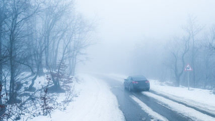 Car on road in foggy snowy forest