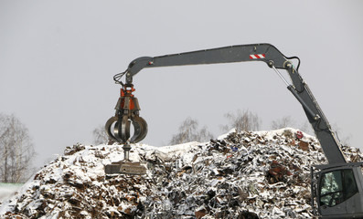 The hydraulic grab cleans and tampens the metal debris. The excavator lifts and throws the load...
