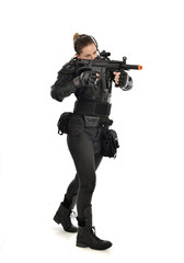Fototapeta premium full length portrait of female soldier wearing black tactical armour, holding a rifle gun, isolated on white studio background.