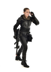 full length portrait of female  soldier wearing black  tactical armour, holding a rifle gun, isolated on white studio background.