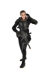 Naklejka premium full length portrait of female soldier wearing black tactical armour, holding a rifle gun, isolated on white studio background.