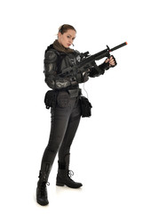 full length portrait of female  soldier wearing black  tactical armour, holding a rifle gun, isolated on white studio background.