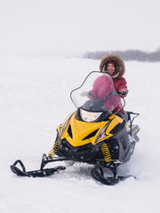Girl in the snowmobile. Winter snow field