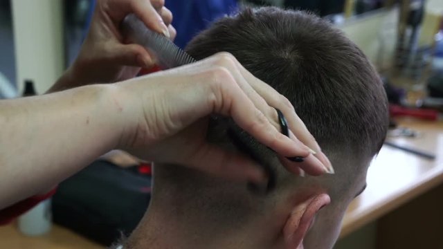 Barber cuts the hair of the client with scissors, close up.