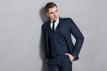 man in blue suit with vest in studio on gray background