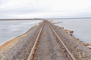 Obraz premium old rusty railroad tracks on gravel embankment at salt mining site Lake Baskunchak, Astrakhan region, Russia