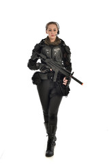 full length portrait of female  soldier wearing black  tactical armour, holding a rifle gun, isolated on white studio background. © faestock