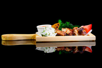 Fried grilled meats with vegetables on a black background