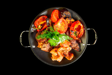 Fried grilled meats with vegetables on a black background