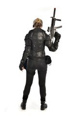 full length portrait of female  soldier wearing black  tactical armour, holding a rifle gun,...