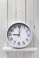 wall clock at wooden shelf