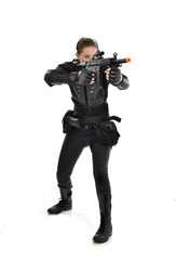 full length portrait of female  soldier wearing black  tactical armour, holding a rifle gun, isolated on white studio background.