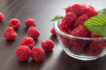 Red raspberries in a bowl on wooden background