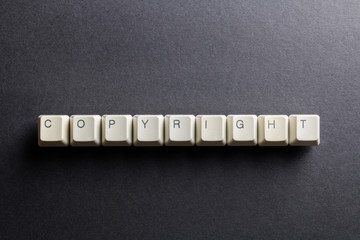 Word copyright made using computer keyboard buttons on a black background. Legal right. IT technology concept.