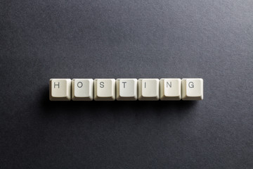 Word hosting made using computer keyboard buttons on a black background. Internet hosting service. IT technology concept.