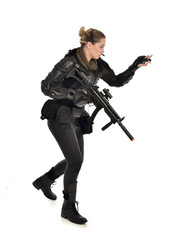 Naklejka premium full length portrait of female soldier wearing black tactical armour, holding a rifle gun, isolated on white studio background.