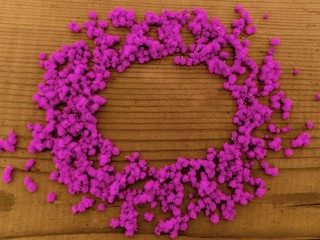 Round pink flowers frame. Round frame of purple pink little flowers on wooden background. Text plase in round frame of pink-purple little flowers on wooden table. Top view of round pink flowers frame