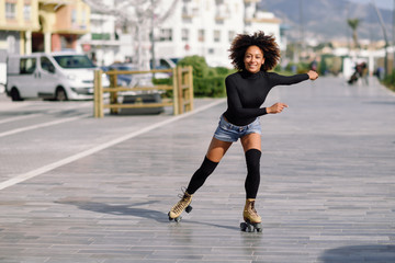 Black woman on roller skates riding outdoors on urban street