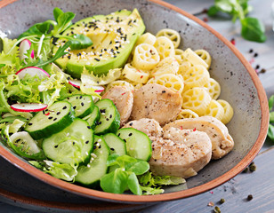 Healthy salad with chicken, avocado, cucumber, lettuce, radish  and pasta on dark background. Proper nutrition. Dietary menu. Dinner.