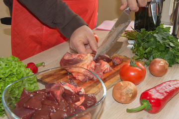 Cook hands with raw meat and vegetables in kitchen