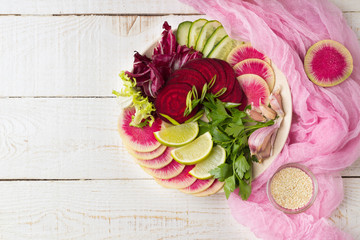 Fresh salad with beets, watermelon radish, cucumber, parsley, lime, garlic, olive oil, mix salads. Healthy concept. White background. Flat lay. Top view.