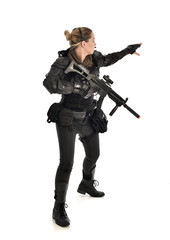full length portrait of female  soldier wearing black  tactical armour, holding a rifle gun, isolated on white studio background.