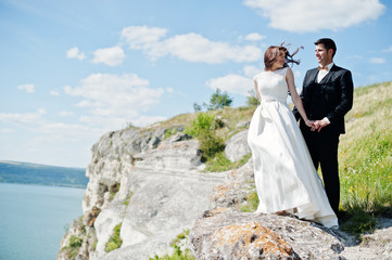 Wedding couple at breathtaking landscape with rock and lake.