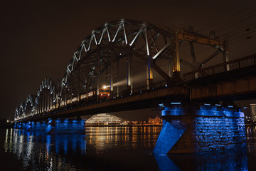 Night railway bridge with blue lights with train. Riga Latvia