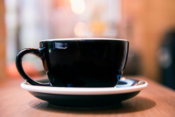 Hot coffee cup on wooden table with blur background