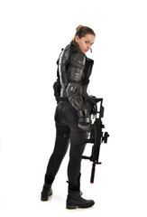 Fototapeta premium full length portrait of female soldier wearing black tactical armour, holding a rifle gun, isolated on white studio background.