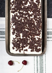 Homemade traditional Black forest sheet cake with cream, shokolate and cherries. Top view. Rustic style and natural light.